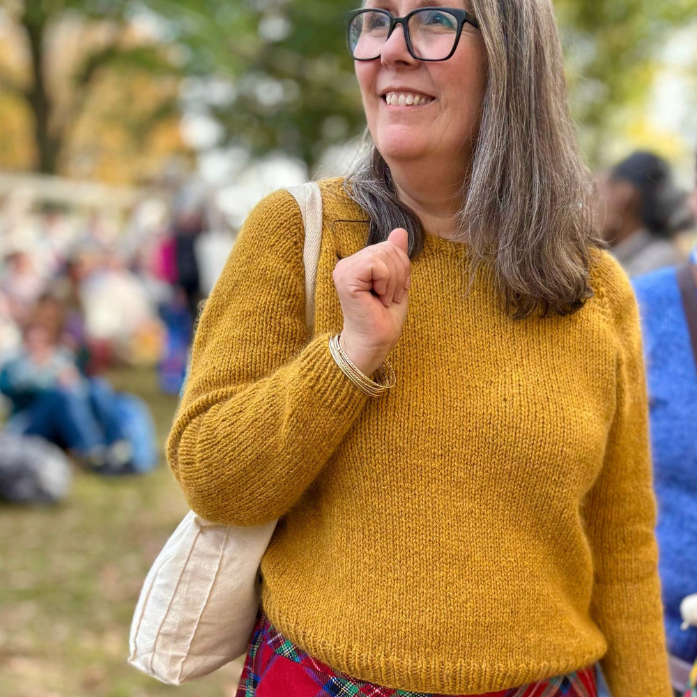 Woman wearing a yellow sweater, design is Vanilla's Big Sister by Corinne Tomlinson.