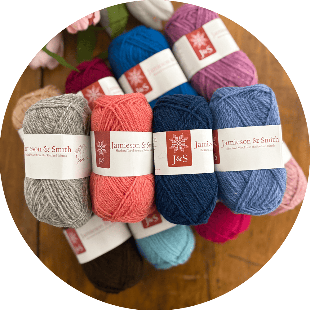 Colorful yarn balls with Jamieson & Smith labels on a wooden surface. Sets of 4 coordinating colors are shown as an example of what may be included in the Box.