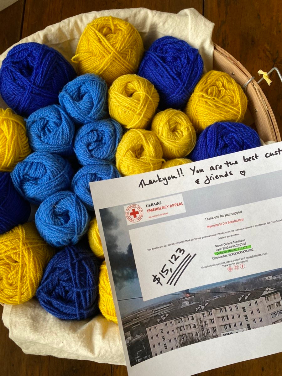 A copy of our donation to Red Cross Ukraine showing proof of our $15,123 donation sits on a basic of blue and gold yarn.