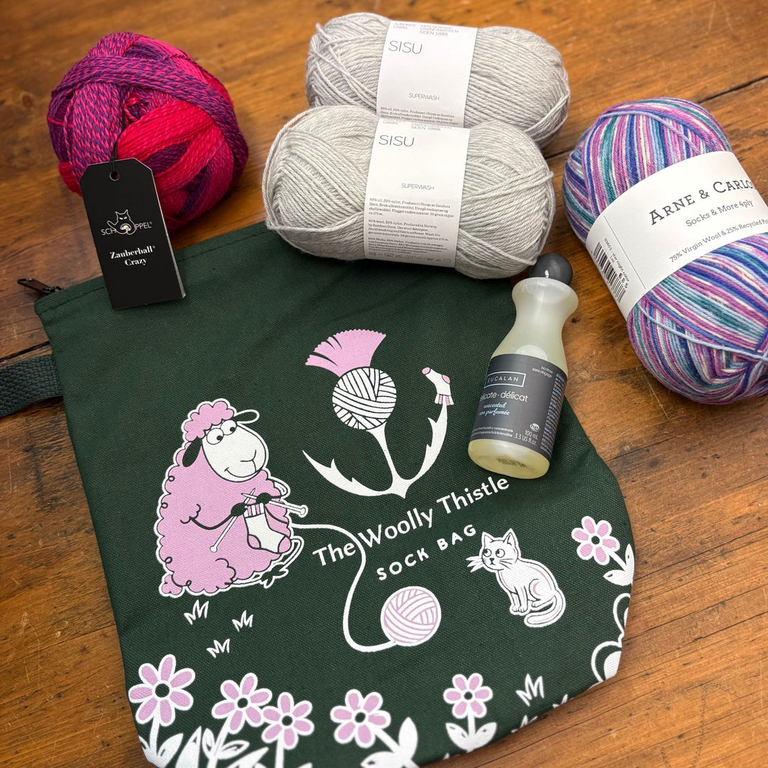 Yarn balls and a bag with 'The Woolly Thistle' branding. This bag is green and called Sockrates' Sock Bag. The bag graphic shows a knitting sheep and cat. 