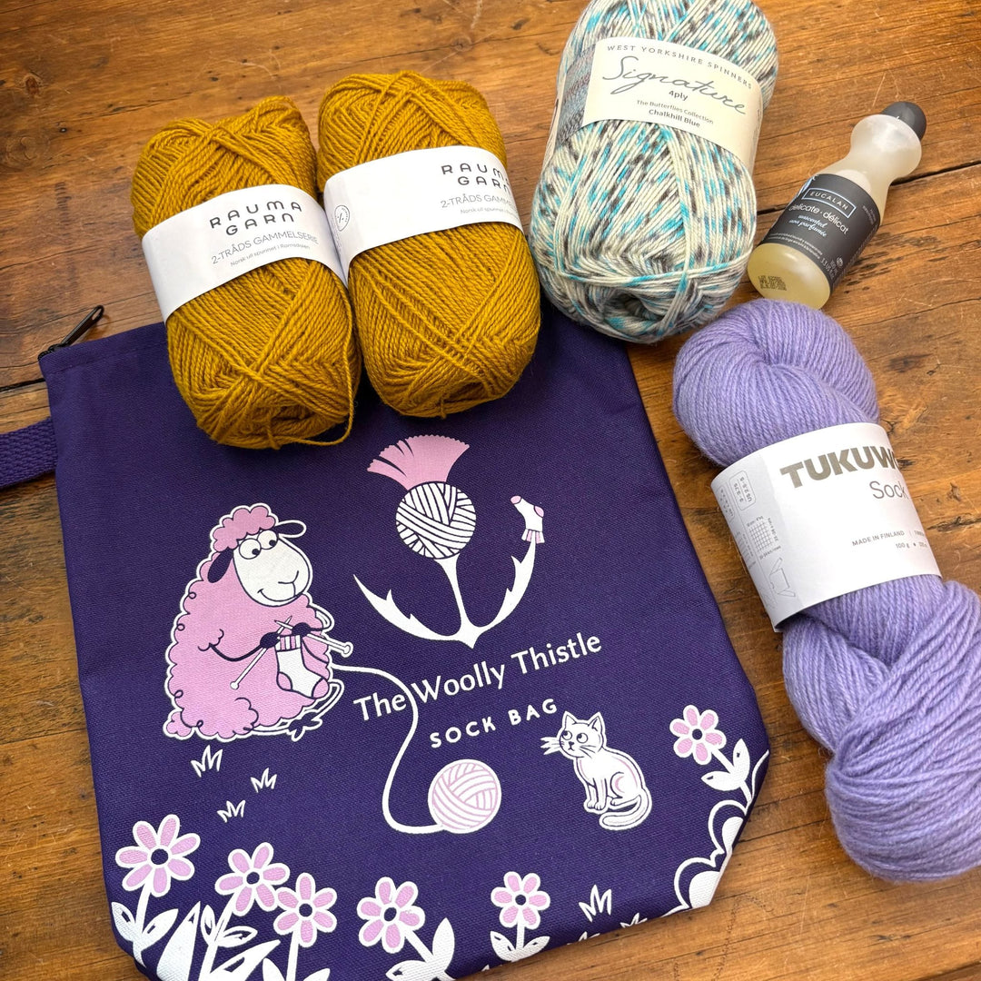 Yarn balls and a bag with 'The Woolly Thistle' branding. This bag is purple and called Wooliam's Sock Bag. The bag graphic shows a knitting sheep and cat. 
