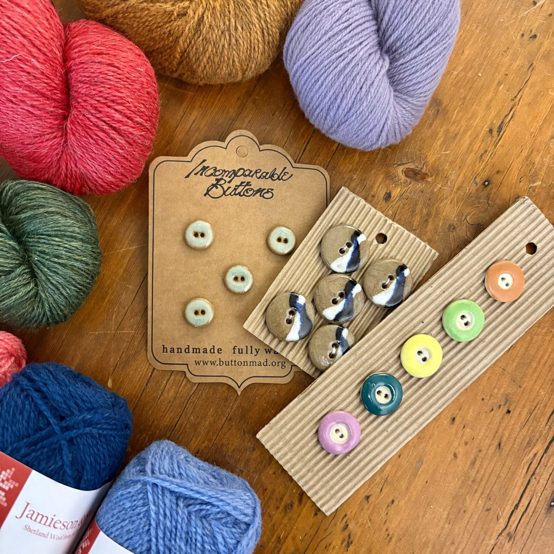 Colorful yarn balls at the edge of the frame and various button sets shown as an example of what is included in the Spring Taster Box. 