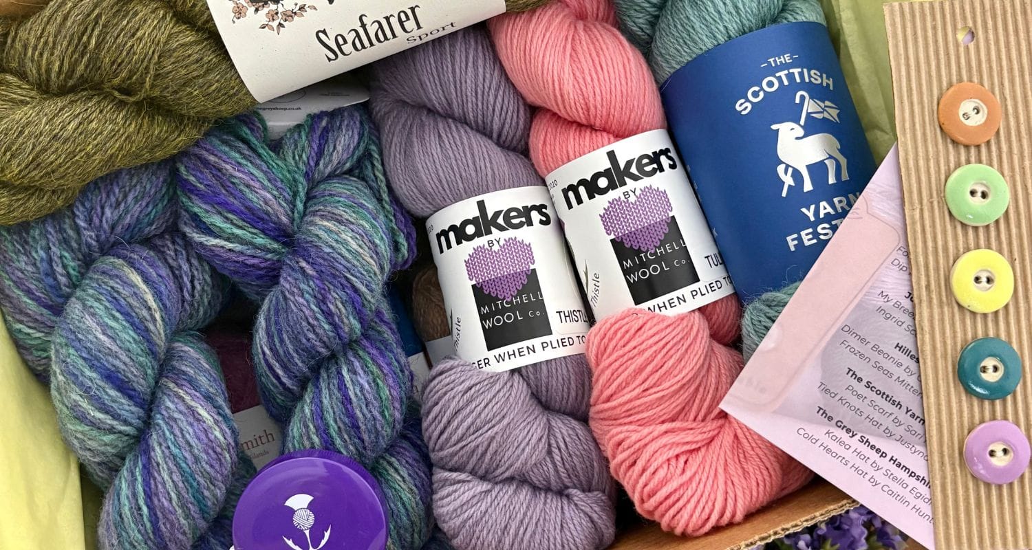Box full of yarns included in the 2026 Taster Box including The Grey Sheep, Mitchell Wool Co, The Scottish Yarn Festival, and John Arbon Sea Farer Sport. Button set shown off to the side.