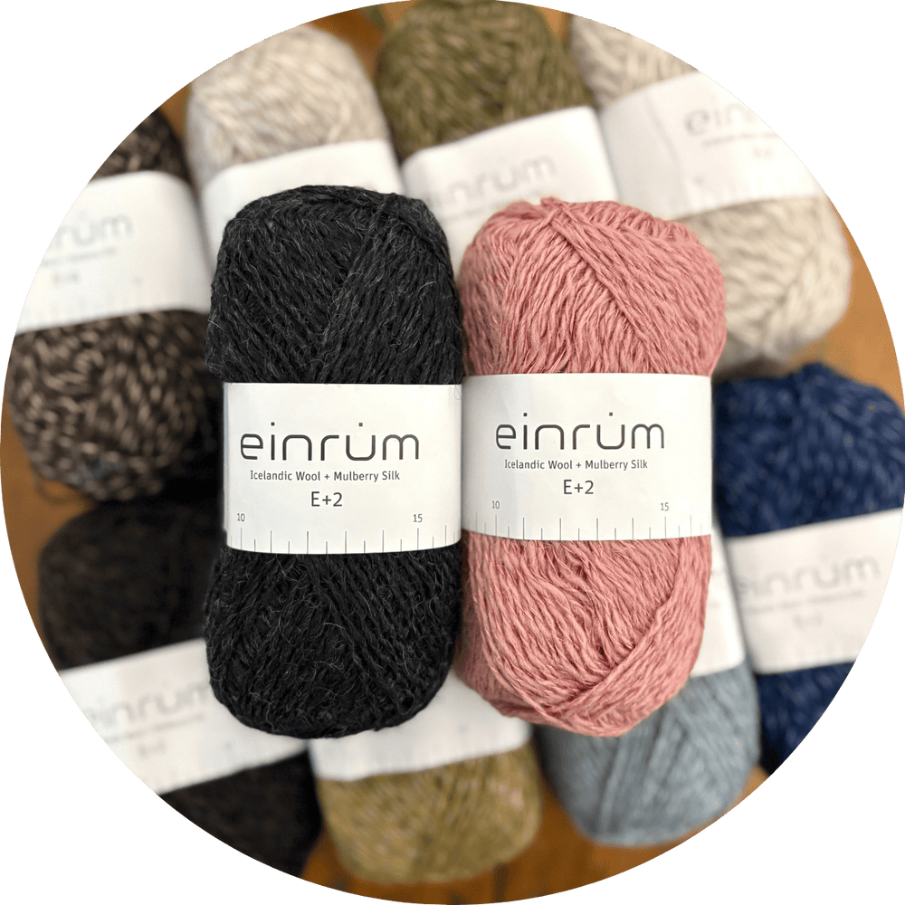 Einrum Icelandic Wool + Mulberry Silk yarn balls shown in a variety of colors with a coordinating black and pink balls sitting on top of the others.