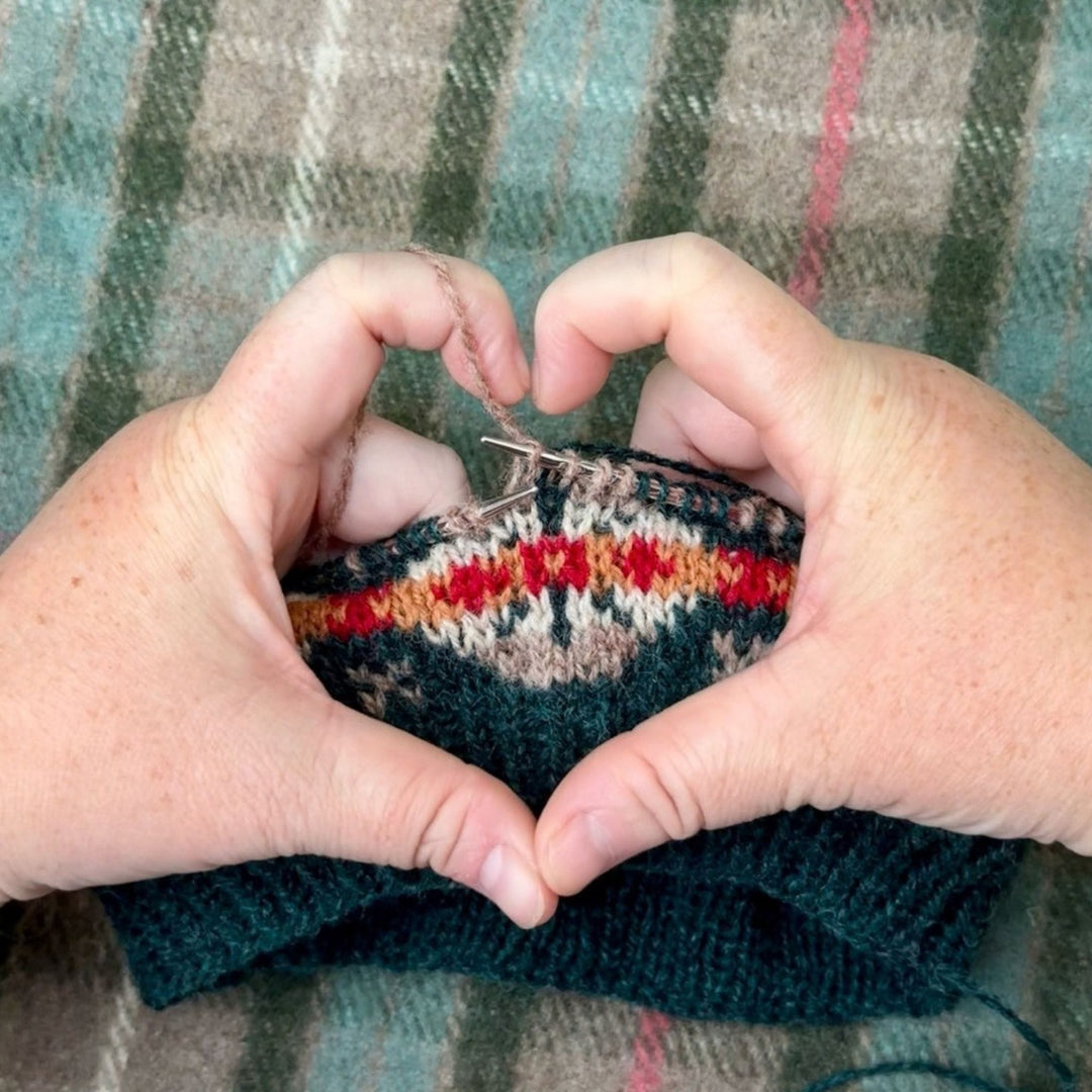 Fair Isle knitting framed by fingers making heart shape