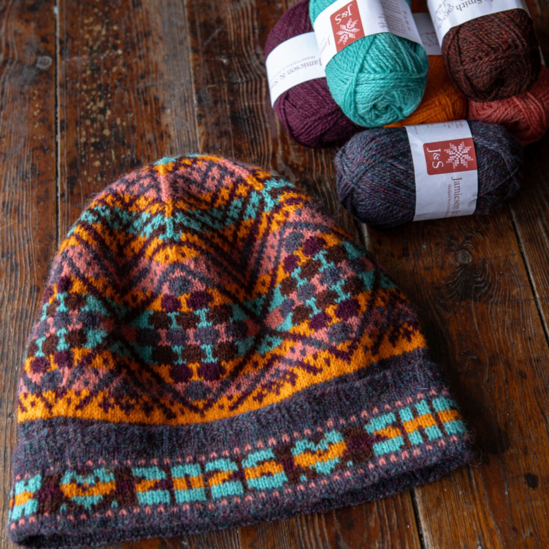 Birsie Beanny colorwork knit hat shown with balls of J&S 2ply Jumper Weight yarn. 