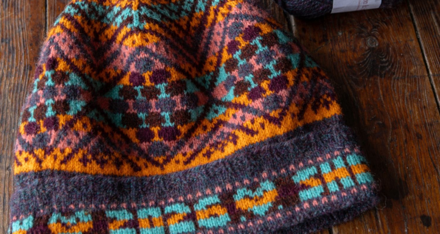 Birsie Beanny handknit colorwork hat in shades of blue, teal, orange.