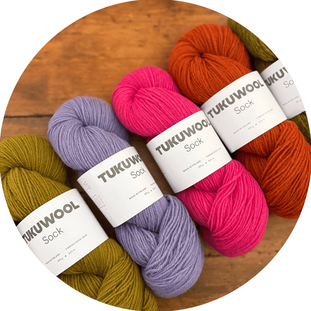 Skeins of colorful yarn on a wooden surface. Labels show yarn is 'TUKUWool Sock'.