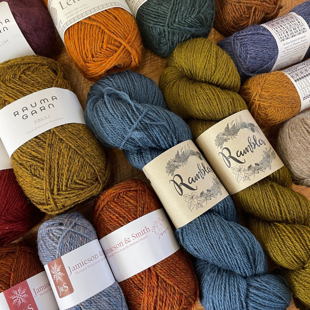 Yarn in mixed colors fills frame.  Labels show Rauma Garn, Jamieson & Smith, Rambler, Marie Walling British reeds, and Lettlopi.