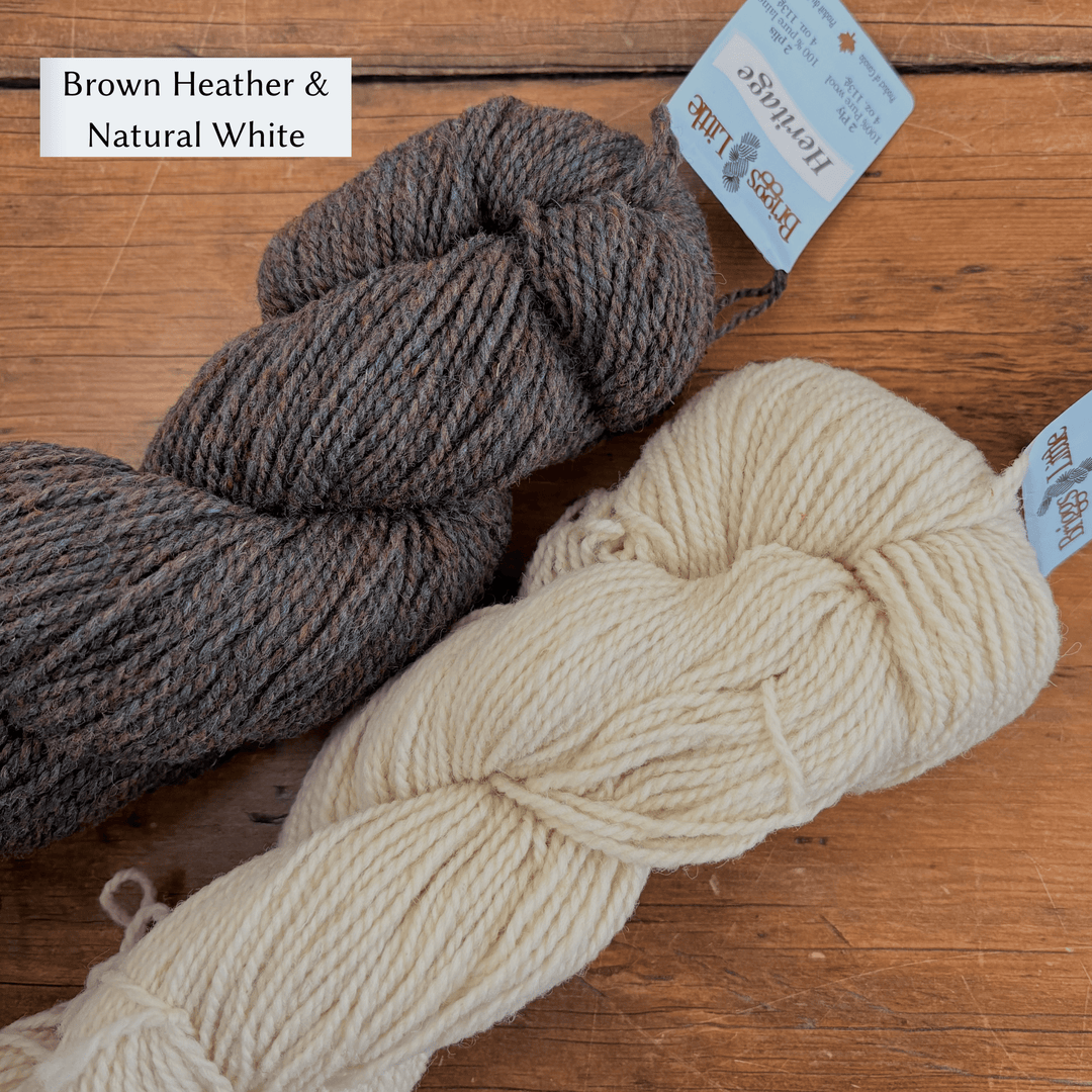 Two skeins of yarn, one brown and one beige, on a wooden surface with 'Brown Heather & Natural White' text. Yarn set designed to knit Overwinter Mittens and Tam designed by Virginia Sattler-Reimer. 