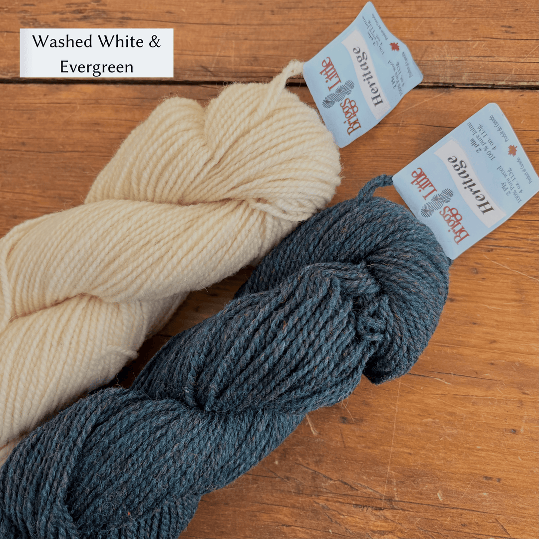 Two skeins of yarn, one white and one gray, on a wooden surface with labels. Yarn set designed to knit Overwinter Mittens and Tam designed by Virginia Sattler-Reimer. 