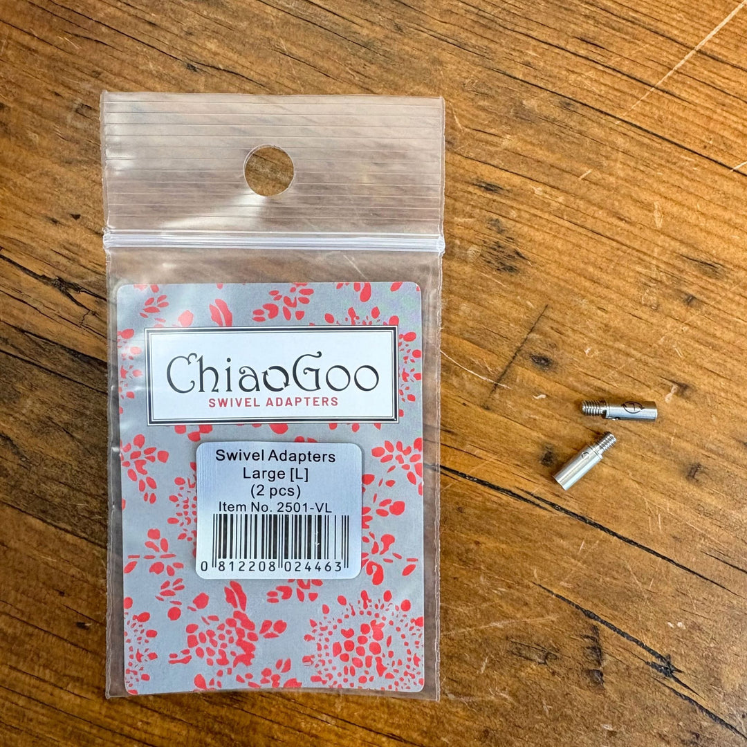ChiaoGoo swivel adapters packaging on a wooden surface with the 2 large swivel adapters next to the package. 