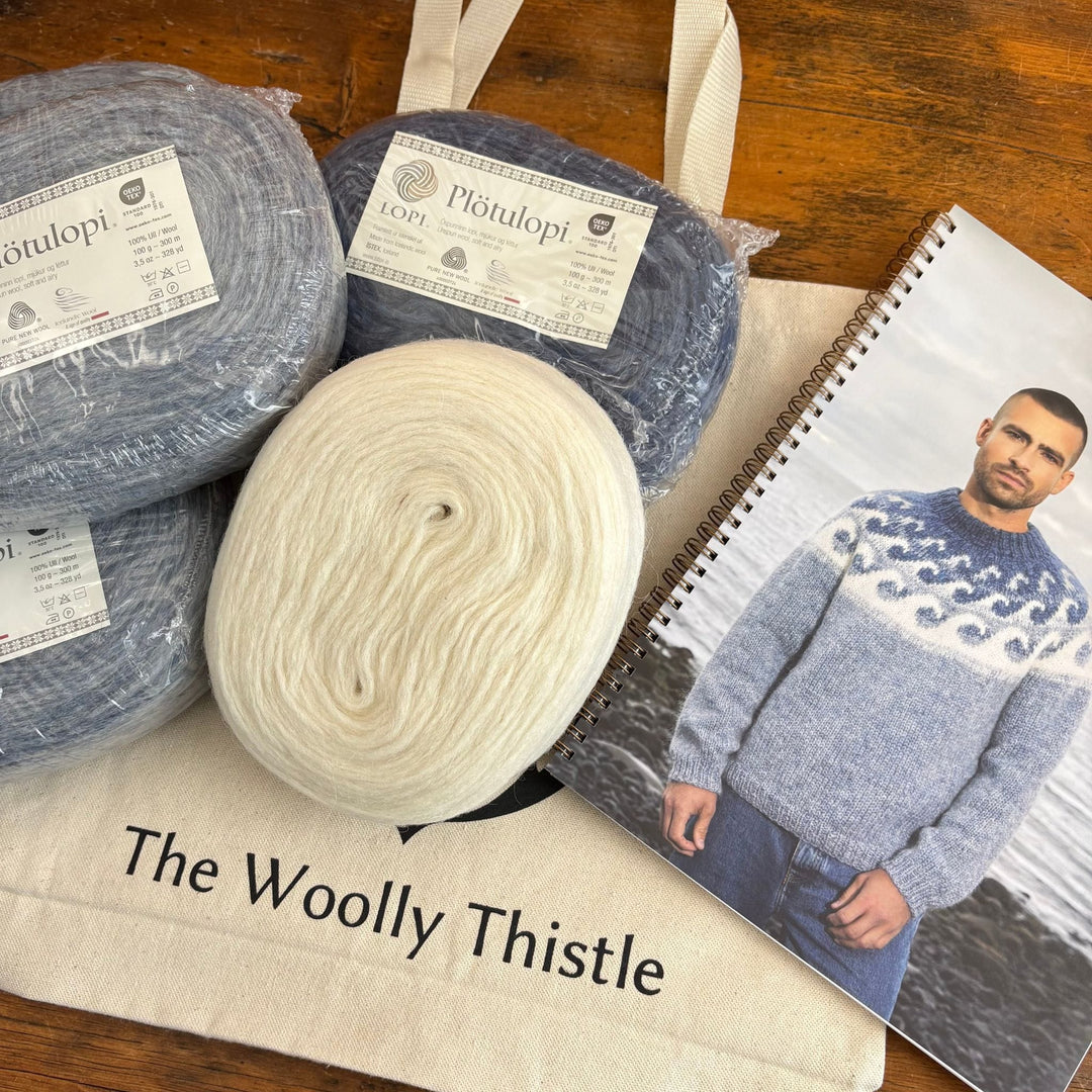 Taken at an angle, Plotulopi Yarn in blue and cream shown with a photo of a man wearing the Brimskafl by  Védís Jónsdóttir. These items on top of The Woolly Thistle tote bag. 
