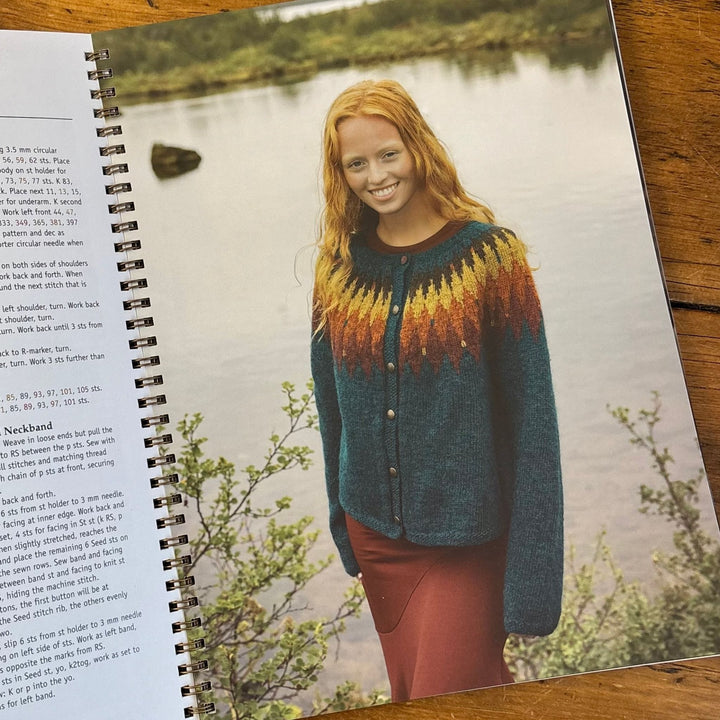 Shows page from Lopi Book 45 Autumn. Book open to a page with a model wearing a colorful knitted cardigan by a lake.