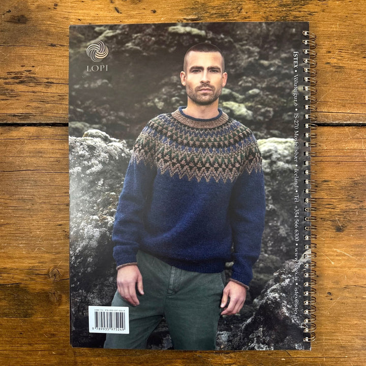 Book back cover of Lopi Book 45 Autumn, shows a man wearing a blue sweater with colorwork yoke. Book is on a wooden surface