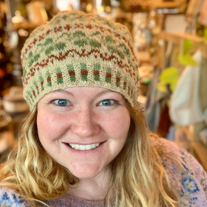 Person wearing the Shamrock Hat by Cait St. George knit in Jamieson & Smith 2-ply Jumper Weight wool with green shamrock colorwork.