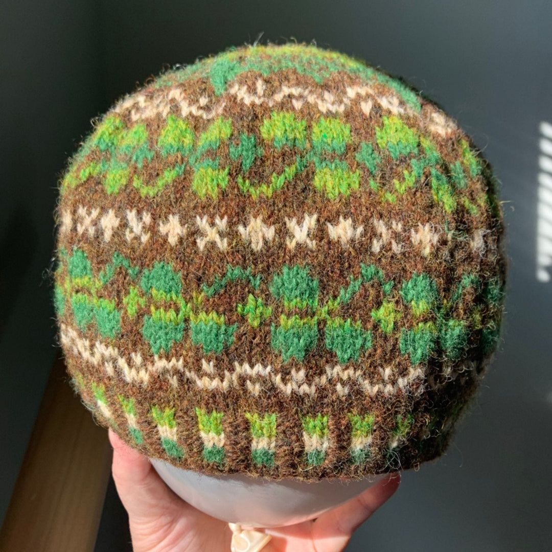 Close view of Shamrock Hat by Cait St. George in Jamieson & Smith 2-ply Jumper Weight, showing green shamrock colorwork on brown background.
