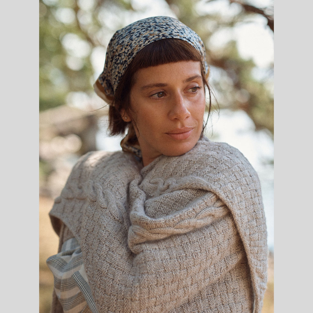 Photo from Laine Issue 28 of woman wearing a patterned headscarf and beige textured shawl outdoors