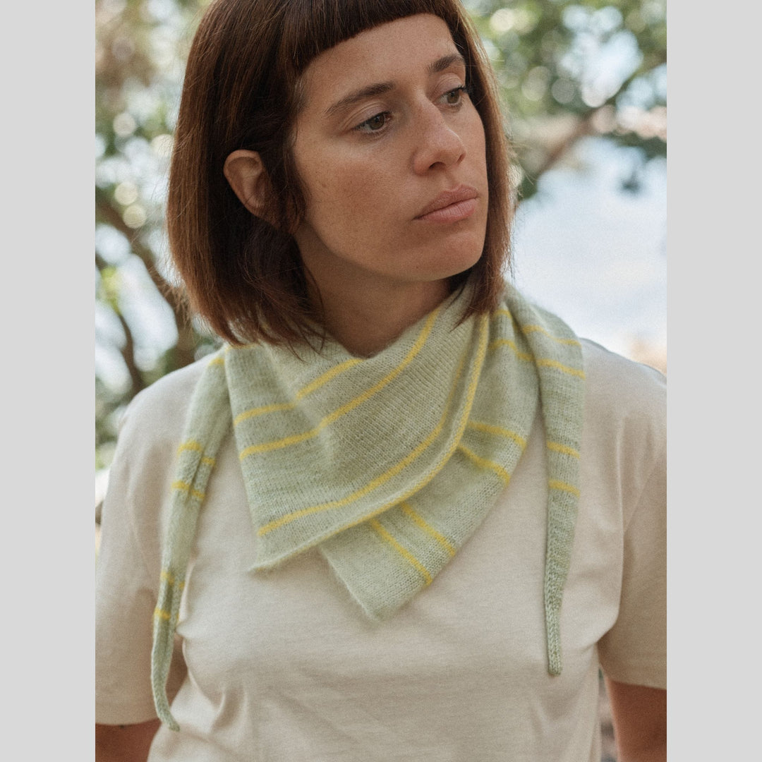 Photo from Laine Issue 28 of a woman wearing a pastel green and yellow striped triangular scarf outdoors