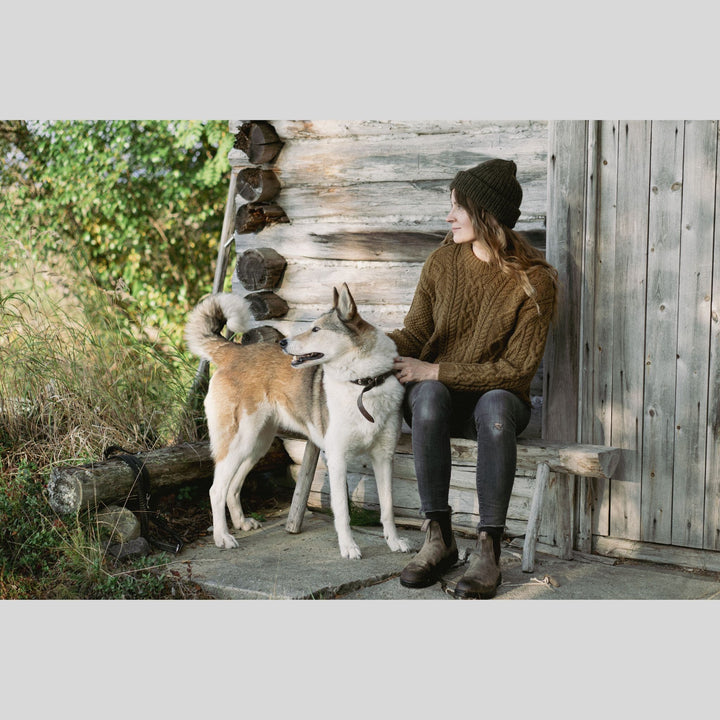 Woman sitting on a wooden bench with two dogs in a natural setting. This is a page from Laine Book "Unfolding Landscapes"
