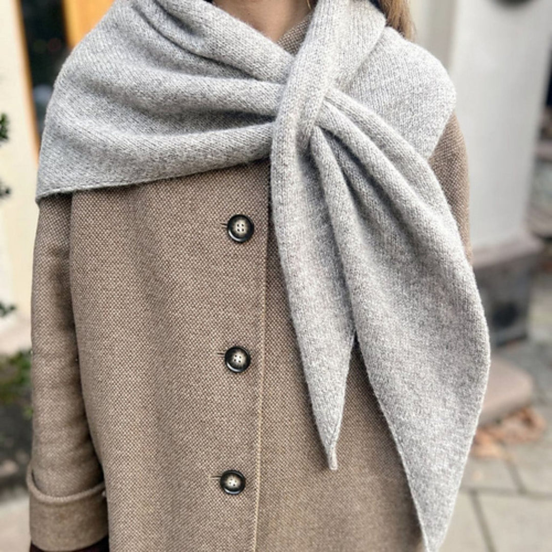 Magdalenasjal shawl knit in Rauma Finullgarn, styled as a soft gray triangular scarf over a coat.