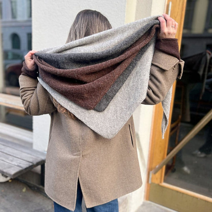 Magdalenasjal shawl in Rauma Finullgarn showing shawls worn overlapping as a large triangular wrap. Shawl colors are light grey, dark grey, and brown. 