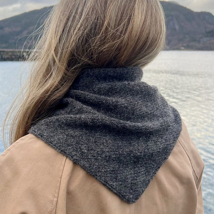 Magdalenasjal shawl knit in Rauma Finullgarn, worn as a triangular scarf in charcoal gray, shown from the back outdoors.