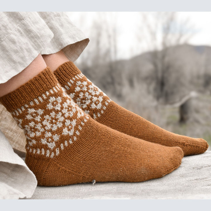 Hellebore Socks by Jessica Mcdonald shown on feet knit in a light brown and natural color Rambler Wool.