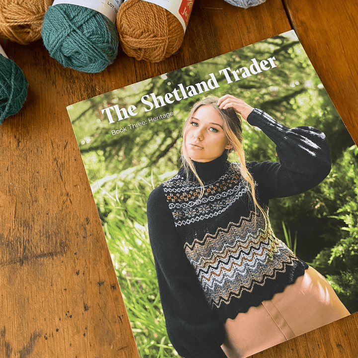 The Woolly Thistle The Shetland Trader - Book Three: Heritage by Gundrun Johnston cover featuring woman wearing knitted turtle neck sweater