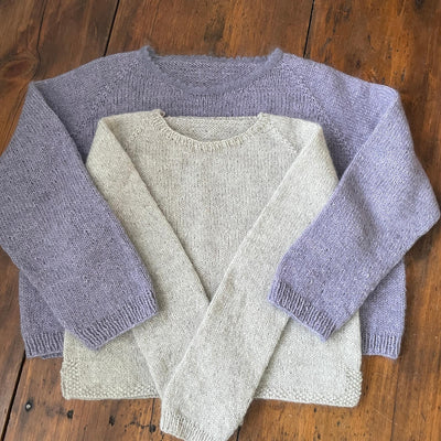 Light Purple sweater with oatmeal colored sweater on top laying out on wooden table 