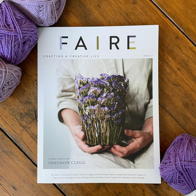 Cover of Faire Magazine Issue 4 with purple yarn around. 