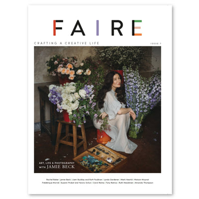 Cover of Faire Magazine Issue 7. White background with photo of woman sitting in room with flowers. 