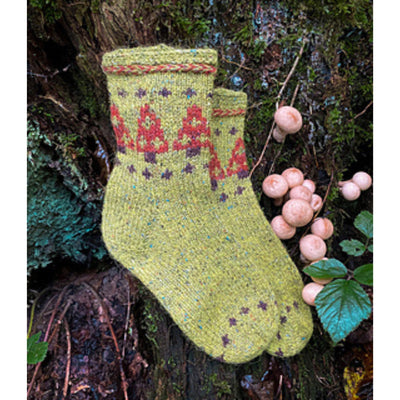 Two light green socks with red mushroom motif, on a forest floor