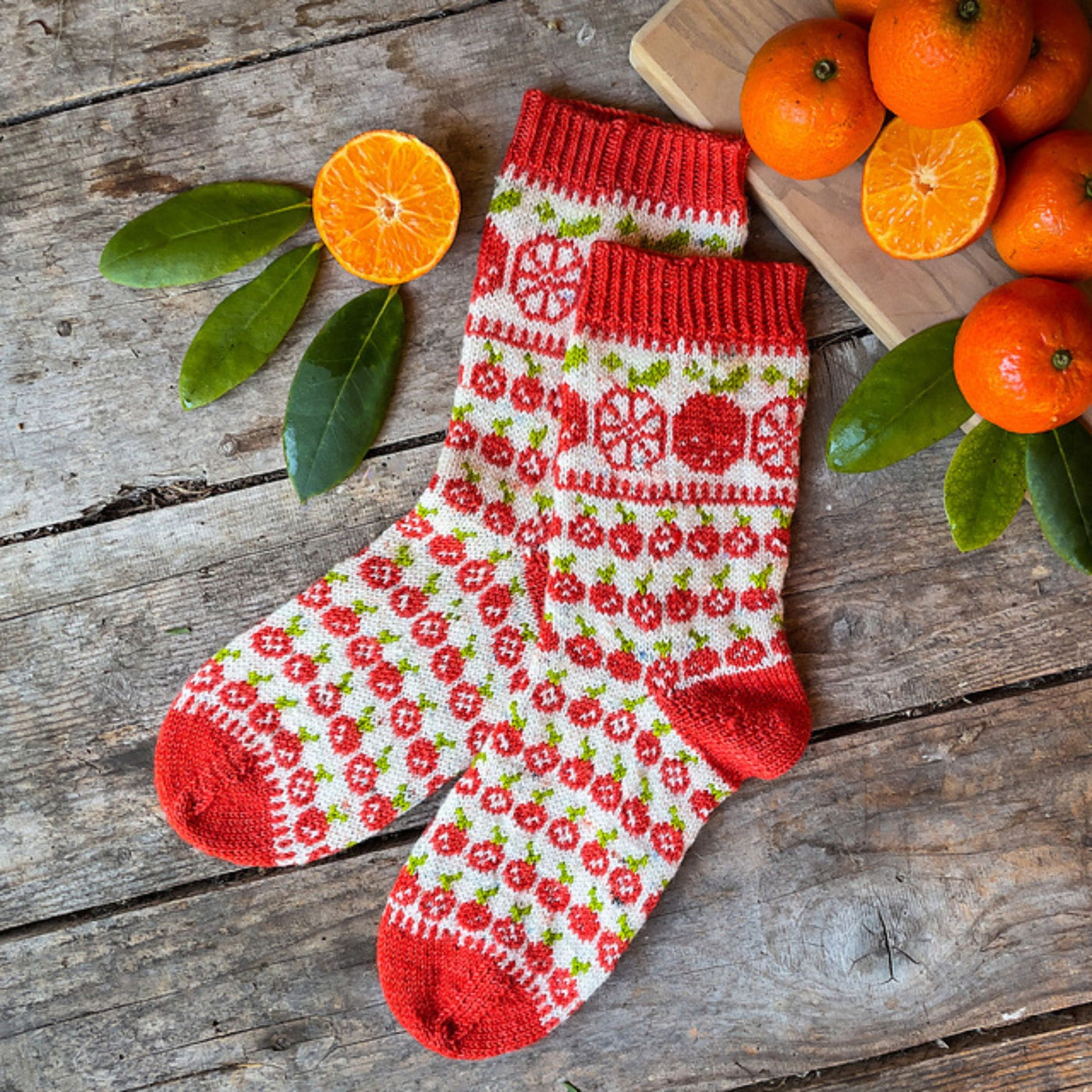 Two white socks on a wooden table near oranges with an all-over oranges motif