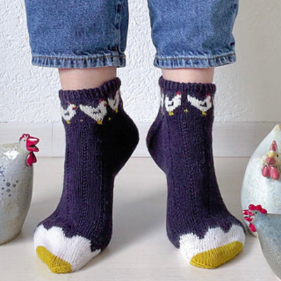 Two feet with navy socks with chicken motifs around the ankles and fried egg motif on the toe