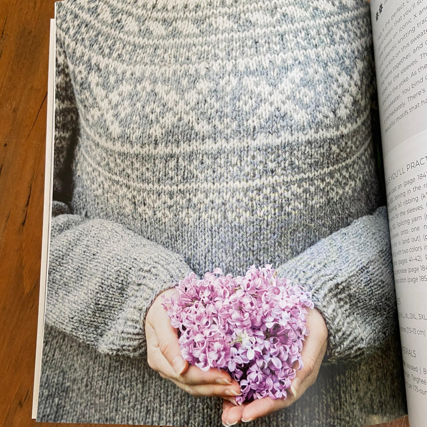 Page of Nordic Knitting Primer book with grey and cream colorwork sweater and hands holding purple flowers.