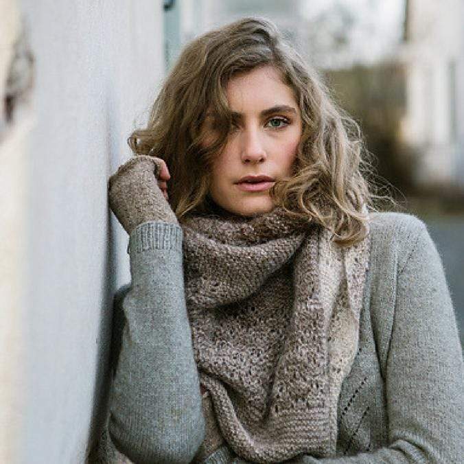 Woman wearing Aito, an asymmetrical shawl in shades of brown with matching mits.