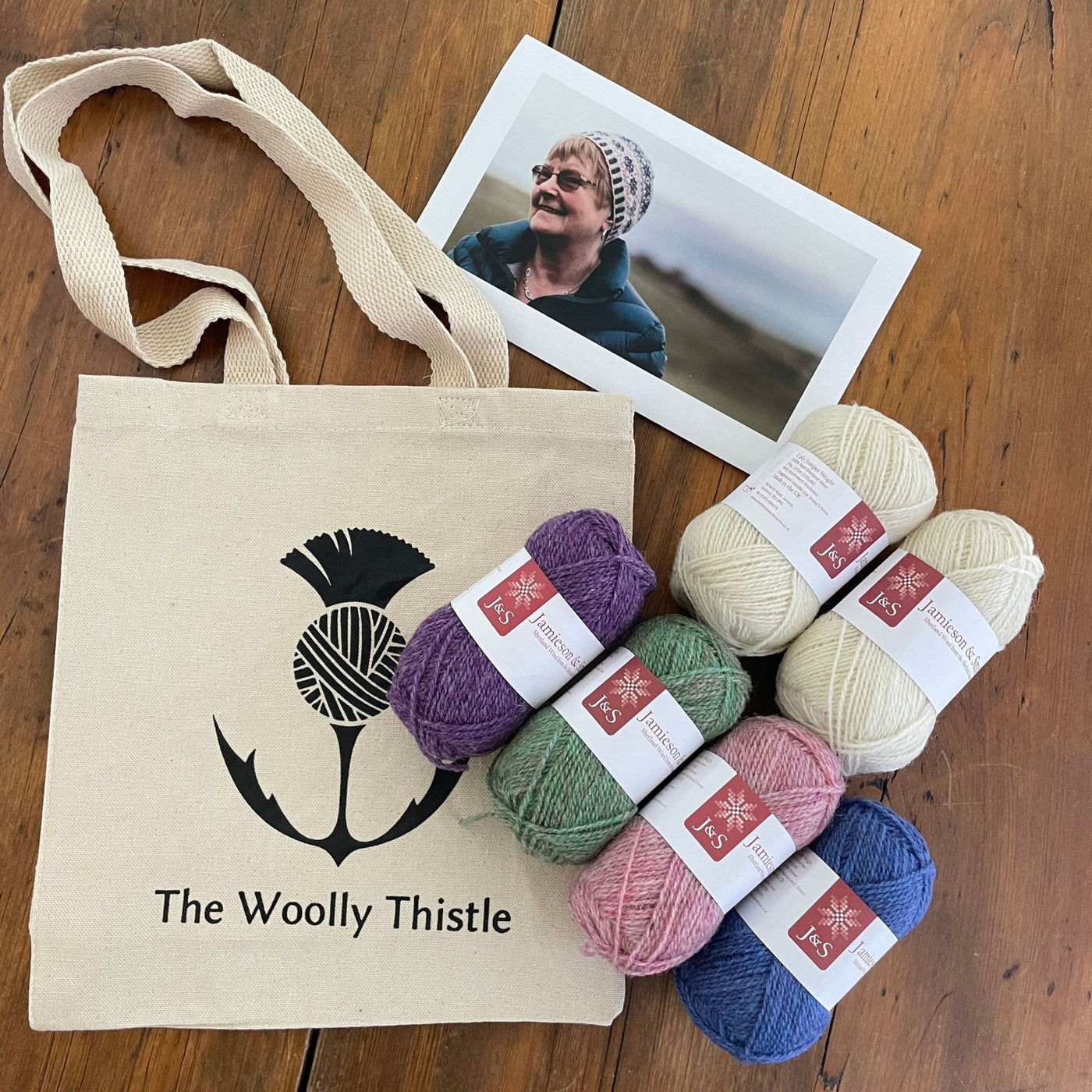 Wilma Malcomson's Katie's Kep Set components shown including 6 balls of Jamieson and Smith yarn shown with photo of woman wearing hat and a TWT tote bag.
