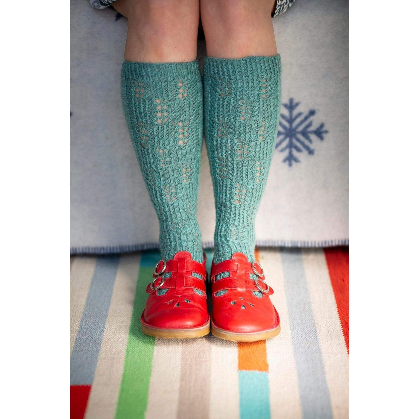 The Woolly Thistle Bluestockings by Kate Davies & Nicole Pohl featuring girl wearing teal knitted socks and red shoes