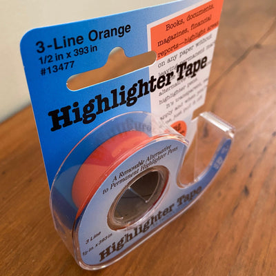 Package of orange highlighter tape sitting on table.