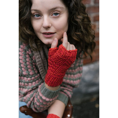 52 Weeks of Easy Knits page shows model wearing one of the knit designs in the book. Closeup view of woman wearing grey and pink knit sweater with red knit fingerless mitts. 