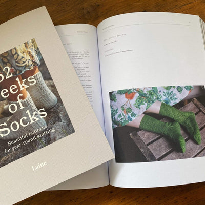 The Woolly Thistle 52 Weeks of Socks: Beautiful Patterns for year-round knitting- paperback edition spread displaying green knitted socks