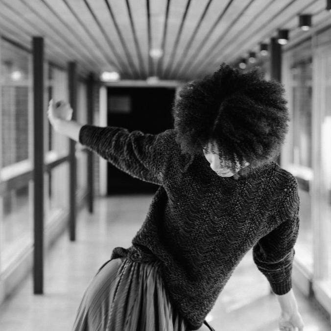 black and white image of model dancing while wearing a knit sweater.
