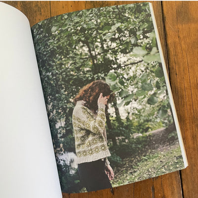 Strands of Joy book page, woman wearing green and tan sweater in woods