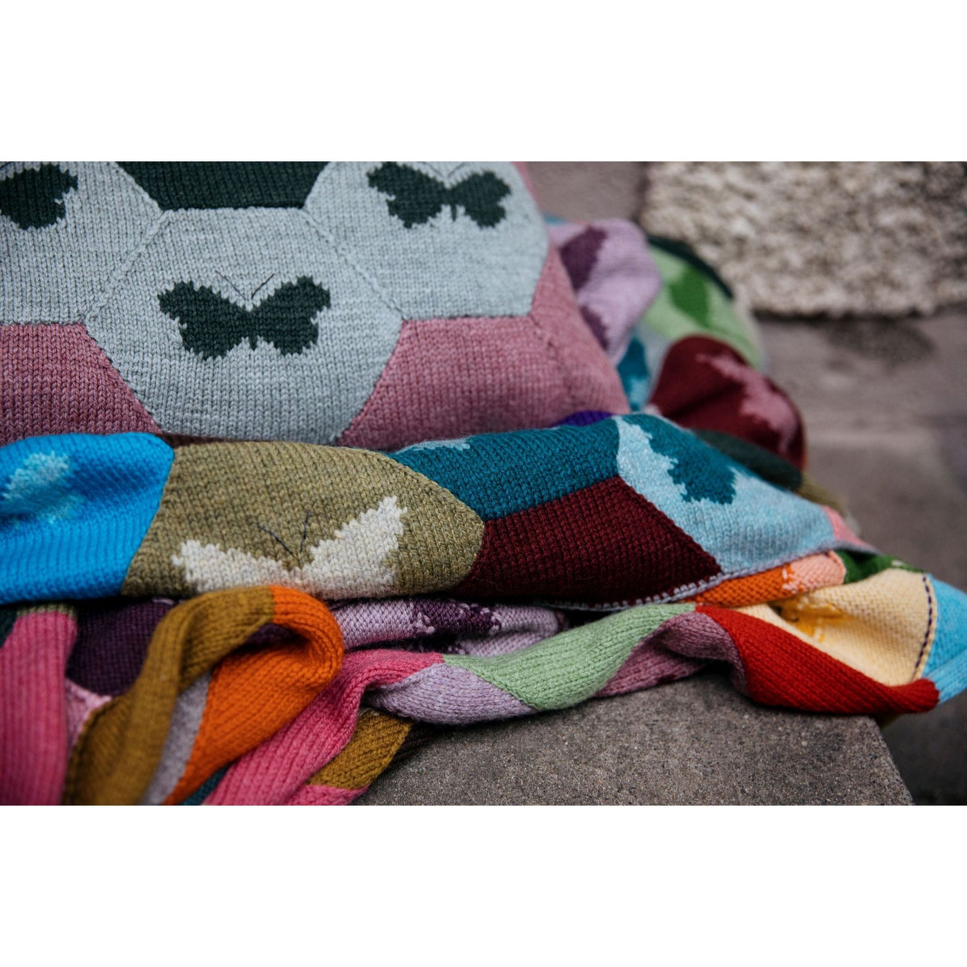 Page from The Knitted Fabric by Dee Hardwicke showing a pillow and blanket with hexagons and butterflies in multiple colors