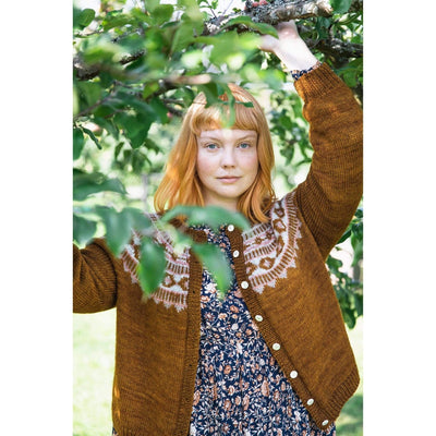 The Woolly Thistle Worsted – A Knitwear Collection Curated by Aimée Gille of La Bien Aimée published by Laine woman wearing brown knitted cardigan with white design on the front