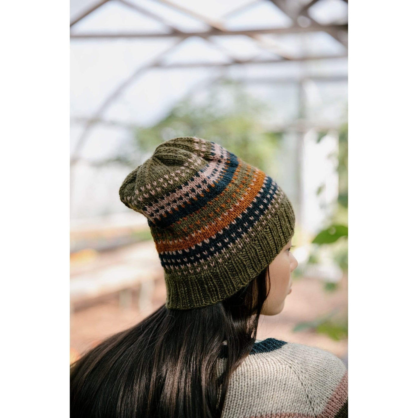 The Woolly Thistle Worsted – A Knitwear Collection Curated by Aimée Gille of La Bien Aimée published by Laine woman wearing green, blue, orange, and beige knitted beanie