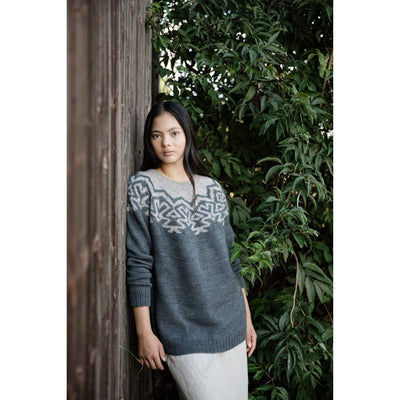 The Woolly Thistle Worsted – A Knitwear Collection Curated by Aimée Gille of La Bien Aimée published by Laine woman wearing grey knitted sweater with light grey design in the front