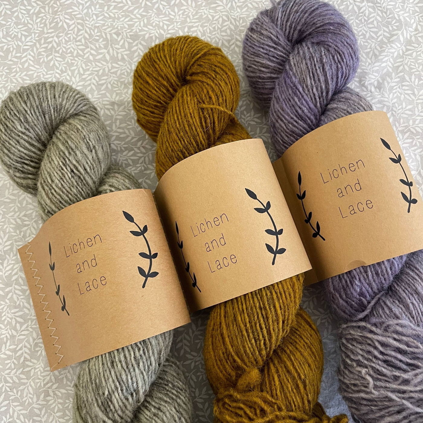 Three skeins of Lichen & Lace Rustic Heather Sport, a sport weight single-ply yarn