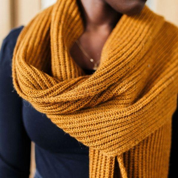 Model wearing a mustard yellow knit scarf.